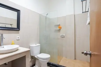 a bathroom with a shower and a toilet and a sink at Prima Inn in Kuta