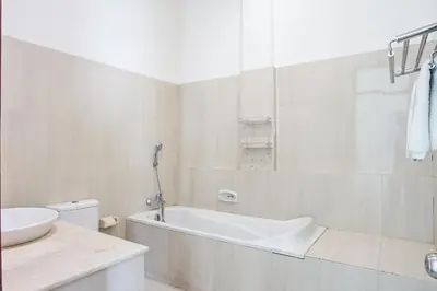 a white bathroom with a tub and a sink at Prima Inn in Kuta
