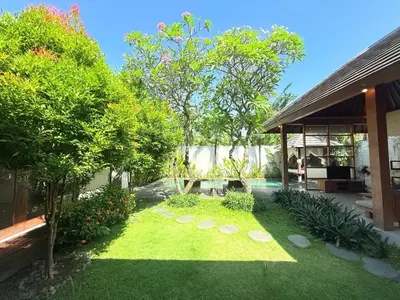 a garden with grass and trees next to a house at Bunga Neil Villa in Seminyak