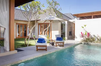 a house with a swimming pool and two chairs next to a house at Bunga Neil Villa in Seminyak