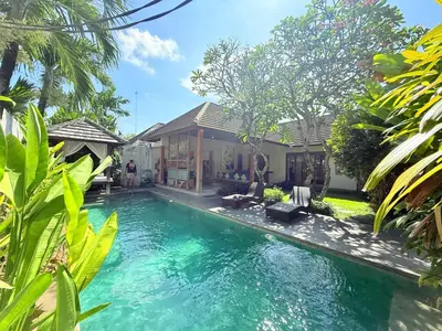 a swimming pool in front of a house at Bunga Neil Villa in Seminyak