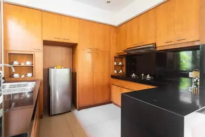 a kitchen with wooden cabinets and a stainless steel refrigerator at Bunga Neil Villa in Seminyak