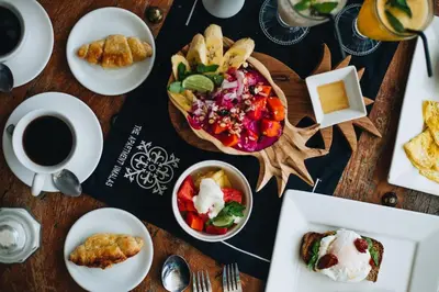 a table with plates of food and a cup of coffee at The Apartments Umalas in Canggu