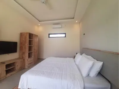 a bedroom with a white bed and a flat screen tv at Villa Rova in Kerobokan