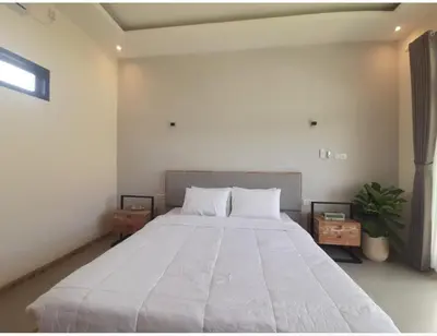 a bedroom with a large white bed with two tables at Villa Rova in Kerobokan