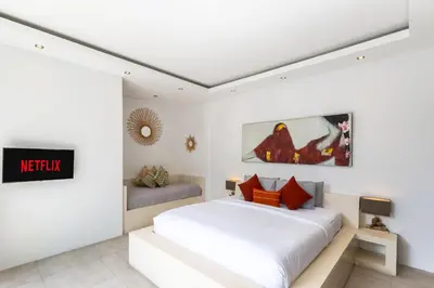a white bedroom with a bed and a tv at Villa Naema by Pertama Management in Seminyak