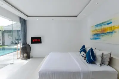 a bedroom with a large bed with blue pillows at Villa Naema by Pertama Management in Seminyak