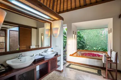 a bathroom with two sinks and a tub with a window at Villa Saffron Seminyak Bali in Seminyak
