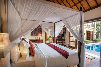 a bedroom with a canopy bed and a swimming pool at Villa Saffron Seminyak Bali in Seminyak