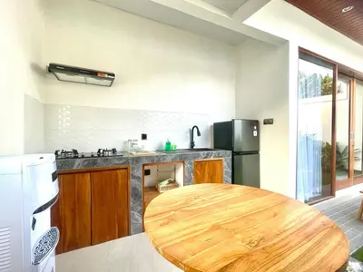 a kitchen with a wooden table in a room at Mahayasa Villa with garden in Canggu