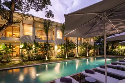 an outdoor swimming pool with lounge chairs and an umbrella at Anam Tang New Rooms & Cafe near Seminyak in Seminyak