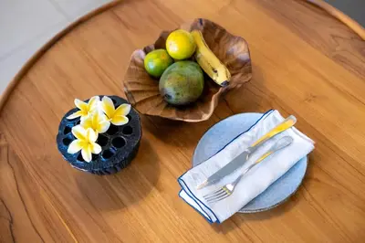 a wooden table topped with bowls of fruit on a table at Anam Tang New Rooms & Cafe near Seminyak in Seminyak