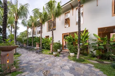 a courtyard with palm trees and a building at Anam Tang New Rooms & Cafe near Seminyak in Seminyak