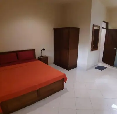 a bedroom with a bed with orange sheets and a cabinet at Rach APT in Kerobokan
