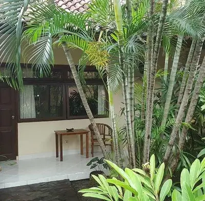 a room with a table and some palm trees at Rach APT in Kerobokan
