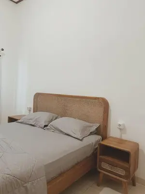 a bedroom with a bed with a wooden headboard and a table at Sukanadi's Homestay in Legian