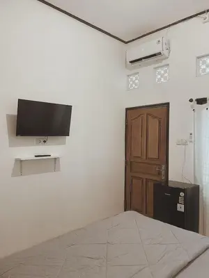 a bedroom with a bed and a flat screen tv on the wall at Sukanadi's Homestay in Legian