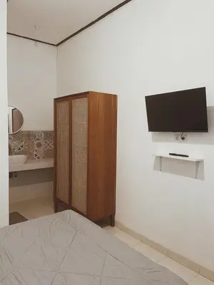 a bedroom with a tv on a white wall at Sukanadi's Homestay in Legian