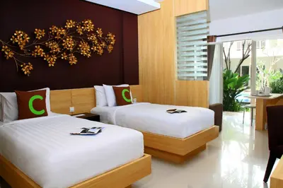 two beds in a hotel room with white sheets at Choice Stay Hotel Denpasar in Denpasar