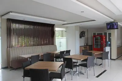 a restaurant with wooden tables and chairs and a television at Choice Stay Hotel Denpasar in Denpasar