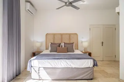 a bedroom with a large bed with a ceiling fan at Heart of Seminyak 2bed 2bath 2 pools super quiet in Seminyak