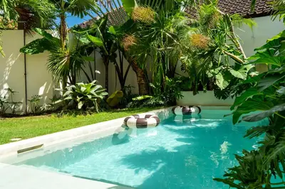 a swimming pool in a backyard with palm trees at 2 bedroom villa with large garden and near Canggu in Kerobokan
