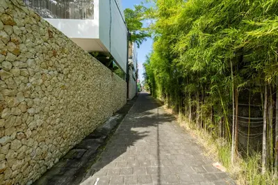an alley with a stone wall and trees at 2 bedroom villa with large garden and near Canggu in Kerobokan