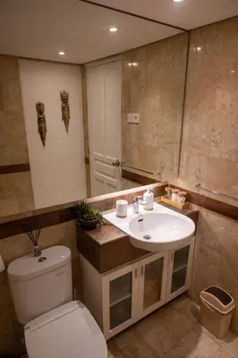 a bathroom with a toilet and a sink and a mirror at Bali Bliss Jayakarta Apartments in Seminyak