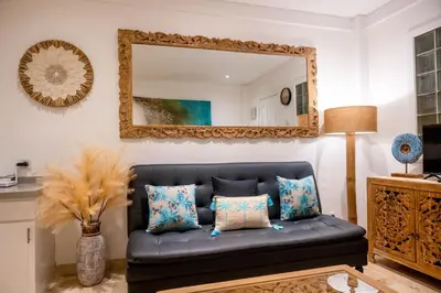 a blue couch in a living room with a mirror at Bali Bliss Jayakarta Apartments in Seminyak
