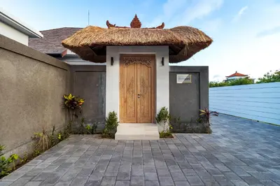 a house with a wooden door and a straw roof at Hiburan Villas in Seminyak
