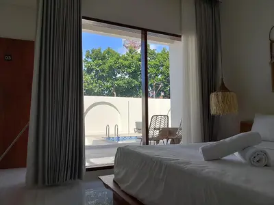a bedroom with a bed and a view of a pool at Apartemen JIRO BALI in Ngurah Rai International Airport
