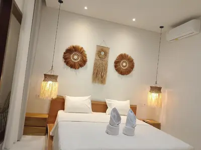 a bedroom with two beds and a clock on the wall at Apartemen JIRO BALI in Ngurah Rai International Airport