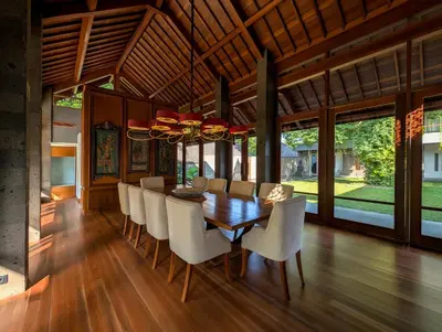 a dining room with a wooden table and white chairs at Jeeva Tirta Seminyak in Canggu