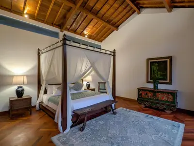 a bedroom with a canopy bed and a wooden floor at Jeeva Tirta Seminyak in Canggu