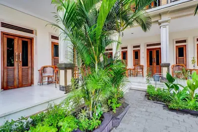 a courtyard of a house with palm trees and chairs at Collection O Budget Door Legian Inn @Poppies Road in Legian