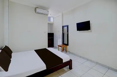 a bedroom with a bed and a tv in it at Collection O Budget Door Legian Inn @Poppies Road in Legian