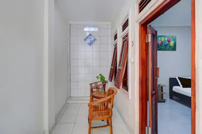 a hallway with a wooden chair and a room at Collection O Budget Door Legian Inn @Poppies Road in Legian