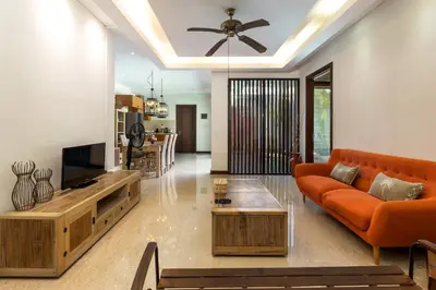 a living room with an orange couch and a television at Tolgay Living Villas in Seminyak