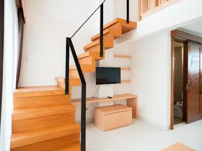 a living room with a staircase with a television at Aspen bali nusa dua in Nusa Dua