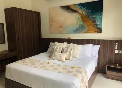 a bedroom with a large white bed with a painting on the wall at Villa Sooni 1 in Seminyak