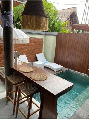 a wooden table and chairs next to a swimming pool at Villa Sooni 1 in Seminyak