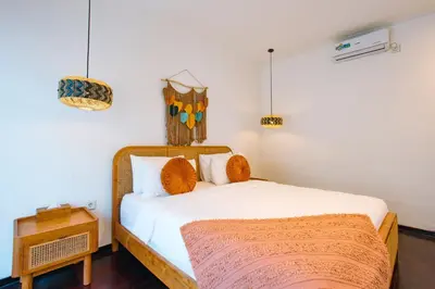 a bedroom with a bed with white sheets and orange pillows at Casa Yo-Na Seminyak in Seminyak