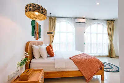 a bedroom with a bed and two windows at Casa Yo-Na Seminyak in Seminyak