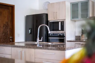 a kitchen with a sink and a black refrigerator at Spacious Charming 4BR Balinese Villa, Seminyak in Kerobokan