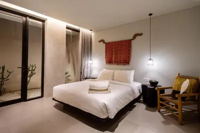 a bedroom with a large white bed and a chair at Hanupis Canggu Apartment in Canggu