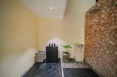 a bathroom with a stone wall and a plant at Villa Ramadewa Beachside with Authentic Charm in Seminyak