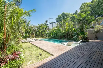 a backyard with a swimming pool and a wooden deck at Tropical 5BR Modern Haven 400m from Canggu in Canggu