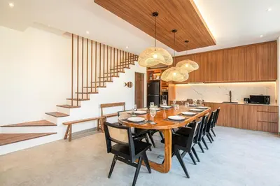 a dining room with a large wooden table and black chairs at Tropical 5BR Modern Haven 400m from Canggu in Canggu