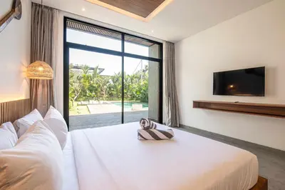 a bedroom with a white bed and a large window at Tropical 5BR Modern Haven 400m from Canggu in Canggu
