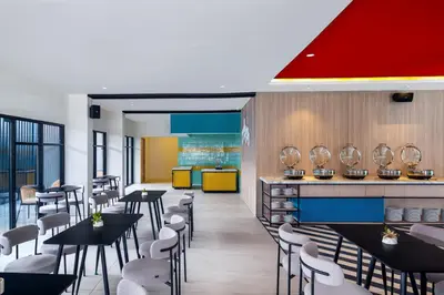 a restaurant with black tables and white chairs at Quest Vibe Dewi Sri Bali in Legian